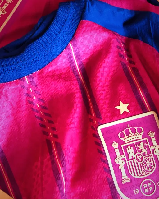 Camisa rosa da Espanha com gola azul e o escudo da federação